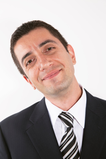 Portrait of a male dressed in business attire looks towards the camera. Male has a confident look on his face.  Image is isolated onto a white background.
