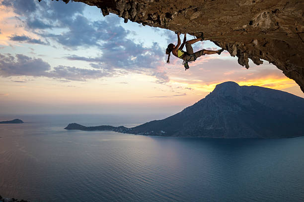 junge weibliche felsklettern bei sonnenuntergang - überhängend stock-fotos und bilder