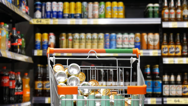 Close-up of a shopping trolley full of beer cans and bottles in a supermarket A shopping trolley cart of beer cans and bottles in alcohol department supermarket close-up grocery shelf cans stock pictures, royalty-free photos & images