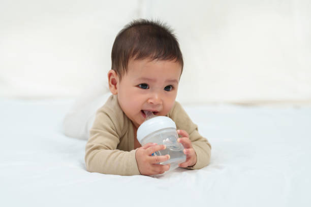 istock baby drinking water from bottle on bed 1795776970