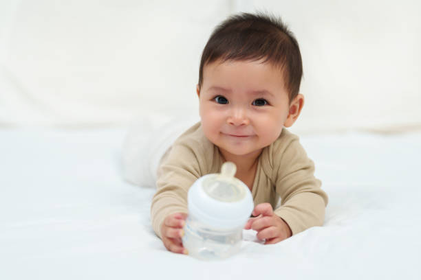 istock baby drinking water from bottle on bed 1795776972
