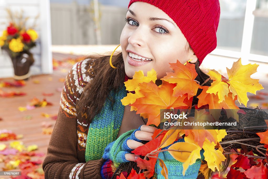 Souriante jeune femme s'appuyant tenant la couronne de l'automne - Photo de Chapeau libre de droits