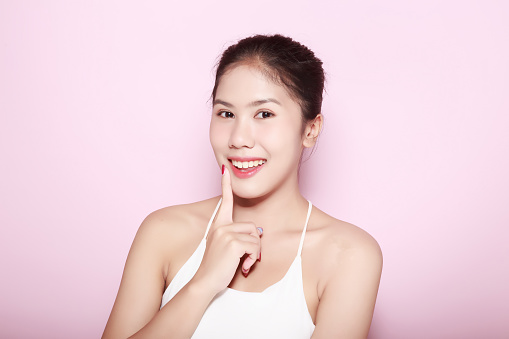 Portrait of beautiful young woman with clean fresh skin on pink background, Face care, Facial treatment. Cosmetology, beauty and spa. Asian women portrait