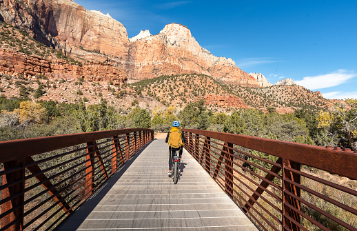 Adult person riding a bicycle along a bridge in Zion National Park. Woman on a relaxing bike ride enjoys the scenery of Zion, Utah