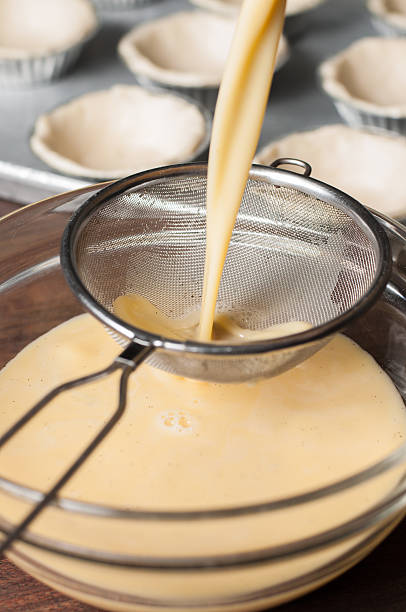 Pou the egg custard mixture into a strainer. stock photo