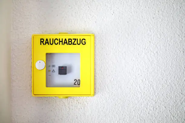 Rauchabzug in German means smoke exhaust. Manual push button from fire alarm system of apartment or commercial building. Selective focus.