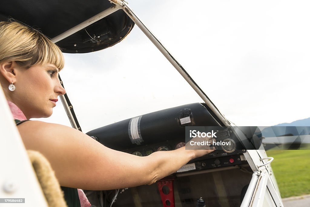 Attractive woman and airplane A young attractive woman sitting in the plane posing as pilot and looking into the control panel. Close up. 20-24 Years Stock Photo