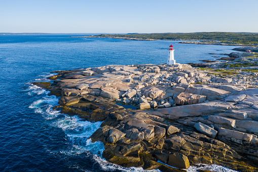 An aerial perspective captures the iconic Peggy's Cove lighthouse, standing sentinel over the serene azure waters of the ocean.