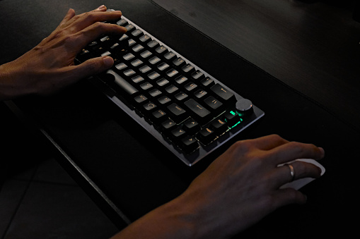 two hands typing on keyboard and operating mouse.