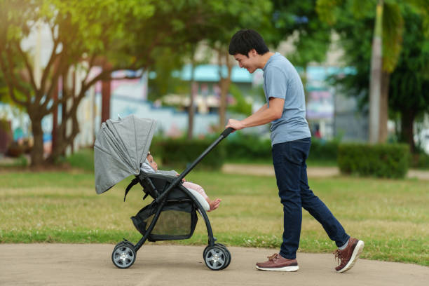 istock happy father looking and pushing infant baby stroller while walking in park 1795995277