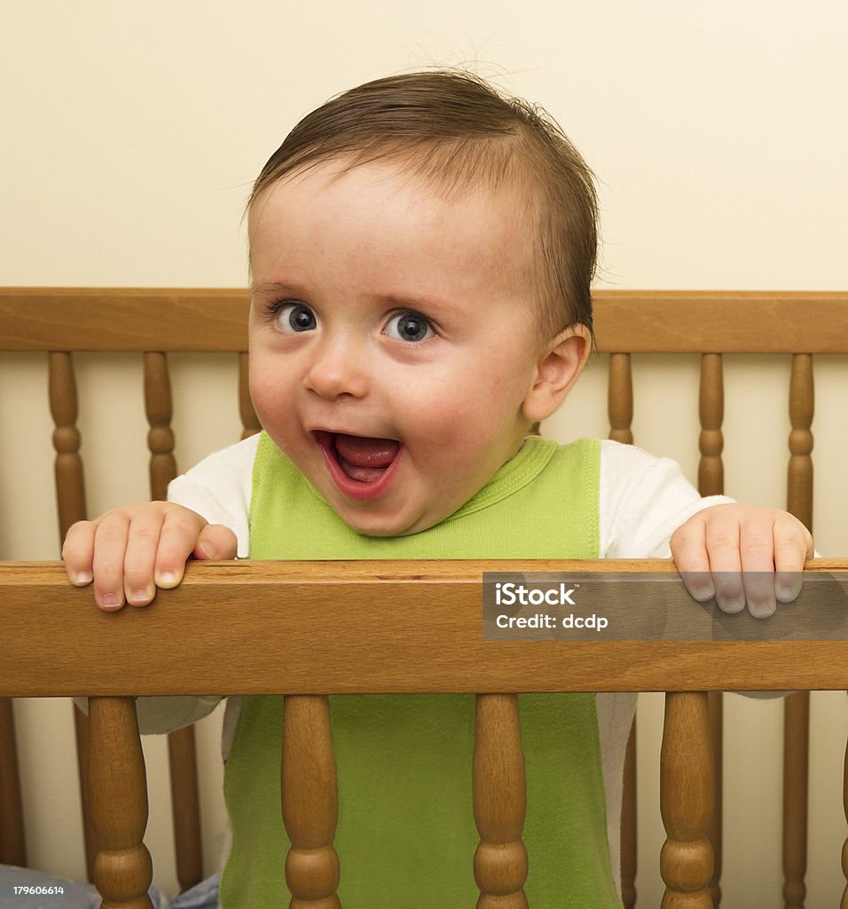 Very happy boy standing in a cot A stock photo of a very happy young boy standing in a wooden cot. 12-23 Months Stock Photo