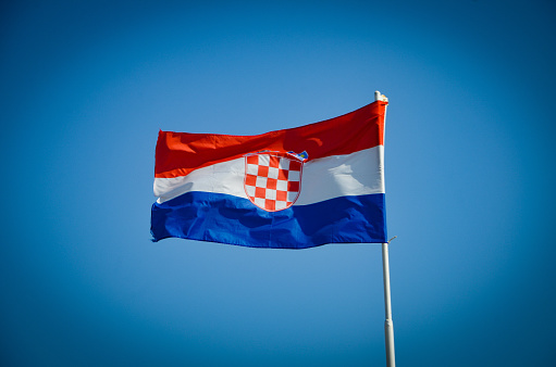 the red, white and blue flag of Croatia flutters in the wind against the blue sky