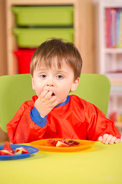 istock Young boy eating fruit in a nursery room 179607740