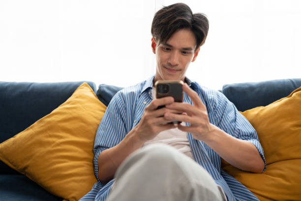 istock Handsome Asia man happy and relax with use smartphone on sofa at home 1796097644
