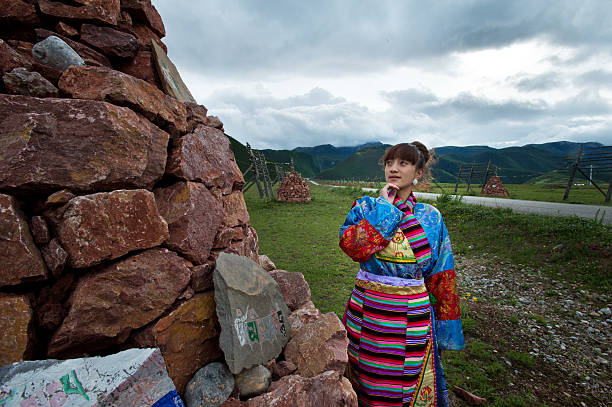 A mother and child stand on a wooden walkway by the lake in Jiuzhaigou. Distant green mountains reflect in the crystal-clear water, with mist swirling around, creating a poetic and picturesque scene