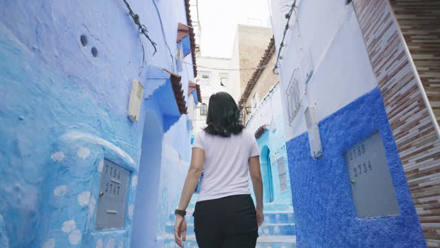Rear-view of unrecognizable female tourist exploring the blue city of Chefchaouen, Morocco