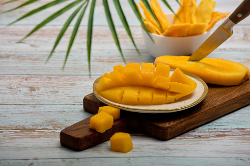 delicious juicy healthy flesh ripe mango is cut with sharp knife on wooden board