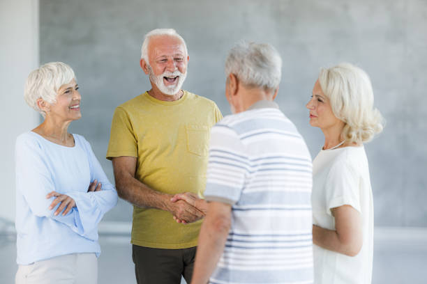 Happy senior men greeting each other next to their wives.