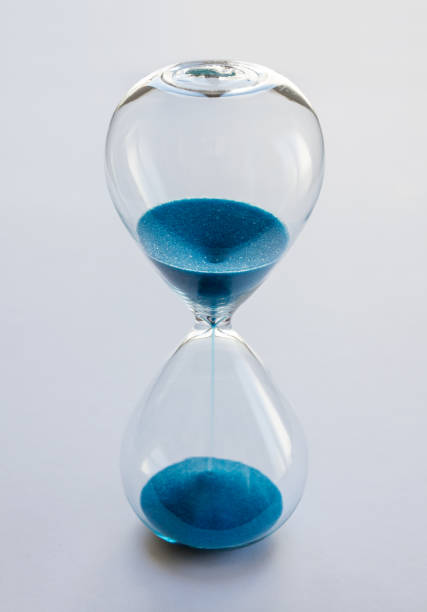 istock Hourglass containing blue sand isolated on white background 1796183528