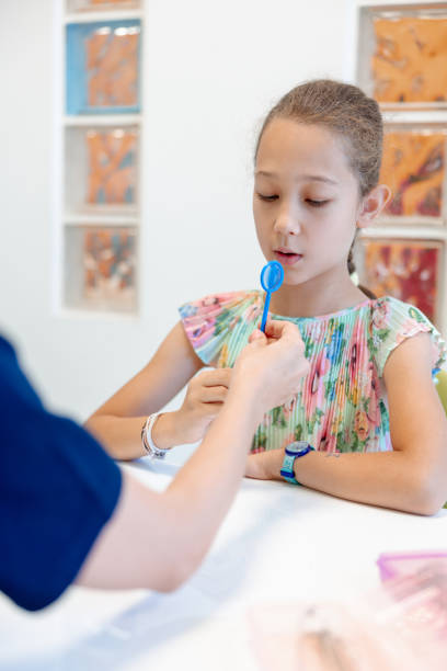 istock Elementary age girl blowing at designed therapeutic aid in speech therapy 1796205215