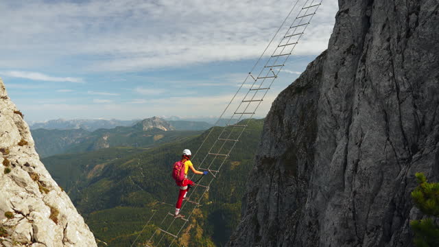 Woman climbing the ladder on via ferrata in Austria