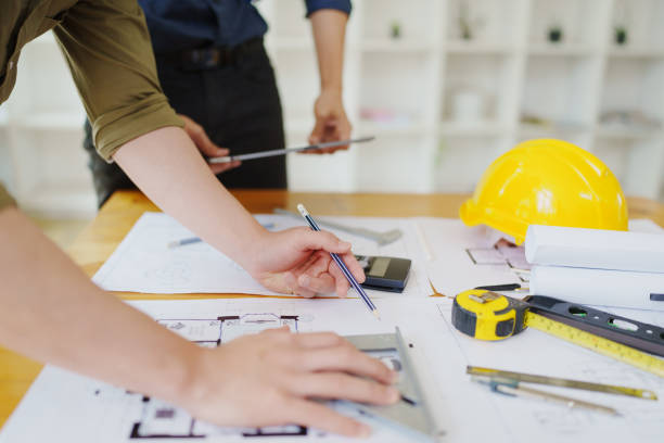 istock multi ethnic engineer brainstorming and measuring for cost estimating on paperworks and floor plan drawings about design architectural and engineering for houses and buildings 1796208392