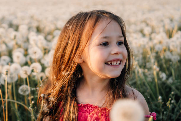 istock Fascinating little lady standing surrounded by white dandelions, smiling happily while looking away, enjoying summer. 1796228391