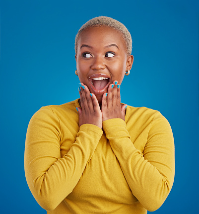Black woman, happy and surprise face in studio for fashion, youth or notification by blue background. Young african girl, model or happiness with excited wow, announcement or deal with hands by mouth