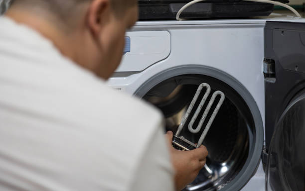 istock A man removed an old heating element from a broken washing machine and inspects it. An old heating element covered in limescale in the hands of a man against the background of a washing machine. 1796235886