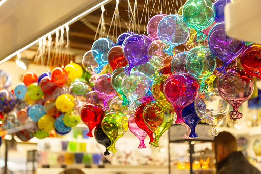 Venetian traditional heritage, multicolored glass balloons hanging on strings on a market stall outdoors in Venice, Italy at the time of winter Carnival