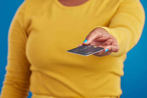 Credit card, payment and woman hand in a studio ready for finance expenses ans sales. Isolated, blue background and ecommerce with a female model showing financial banking method for ecommerce sale