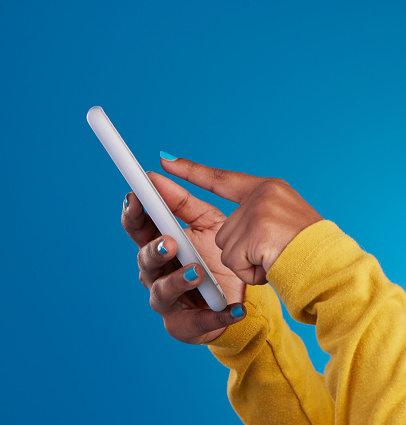 Phone, typing and hands of woman point to screen in studio for social media, text message and website. Communication, technology and girl on internet, networking and chat online on blue background