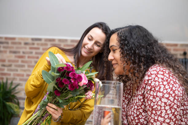 istock Two cheerful women putting a bunch of flowers into a vase 1796290607