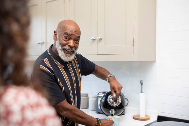 Smiling man making a hot drink in the kitchen at home