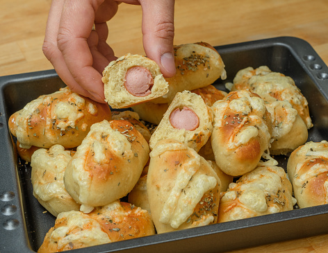 Yeast rolls with sausages on an oven tray
