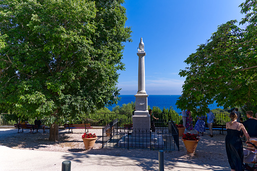 Viewpoint with World War I memorial and pedestrians at village of Giens on a sunny late spring day. Photo taken June 10th, 2023, Giens, France.