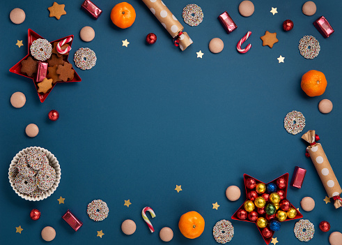 Saint Nicholas Day, 6 December. Christmas card with children's shoes, sweets, candy, gingerbread cookies, gifts on blue background, top view. Traditional winter holiday in Germany and Western Europe.