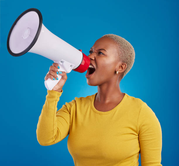 istock Megaphone, shouting and angry black woman in studio for message, broadcast or vote on blue background. Speaker, microphone and girl protest for change, democracy and justice, noise and womens rights 1796335310