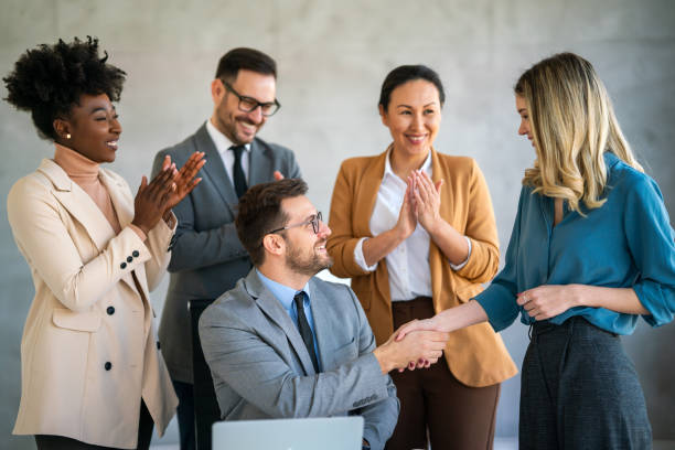 istock Multiethnic business people shaking hands while their colleagues applauding and smiling in office 1796371068