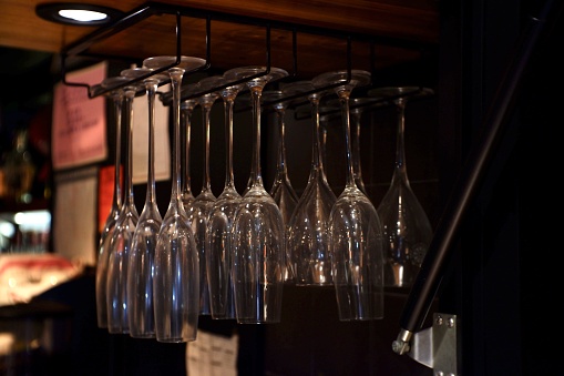 Wine glasses on a rack, at restaurant bar.