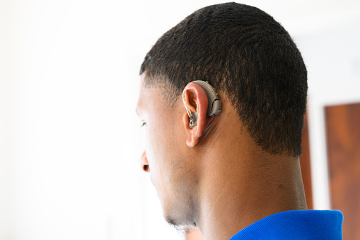 Close up side view young man putting hearing aid in ear