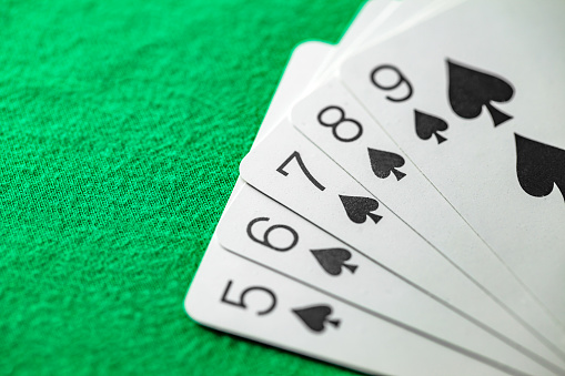 Combinations of cards in poker, straight flush five cards of black peak suit from five to nine, selective focus