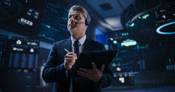 istock Professional Stock Exchange Trader Working on a Tablet Computer. Middle Aged Stockbroker Buying and Selling Shares During Day Trading. Businessman Analyzing Financial and Corporate Data 1796407196