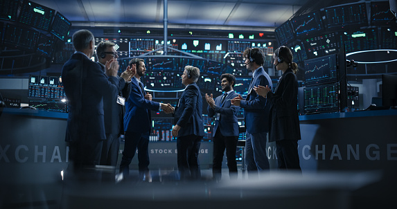 Team of Successful Stock Exchange Brokers Celebrating a Profitable Investment Bid on a Securities Market. Diverse Specialists and Asset Managers Clapping, Cheering, Shaking Hands with the Team Leader