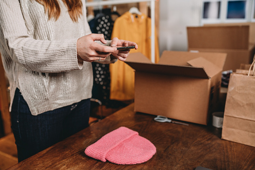 A woman is photographing a pink hat to post a new item on her online shop. Clothing online store. New business concept.