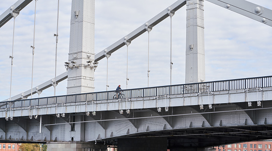 Man riding on bicycle across the bridge in the city. Concept of healthy lifestyle and riding bicycling on city.