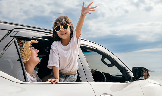 Happy family day. Asian mother father and children smiling sitting in compact white car looking out windows, Summer at the beach, Car insurance, Family holiday vacation travel, road trip concept