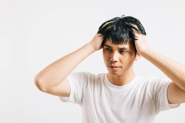 istock Asian man, battling stress and throbbing headache, holds head with a pained expression 1796422329