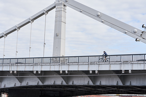 Man riding on bicycle across the bridge in the city. Concept of healthy lifestyle and riding bicycling on city.