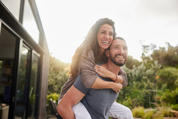 istock Man carrying his wife on his back while having fun outside at home 1796426339